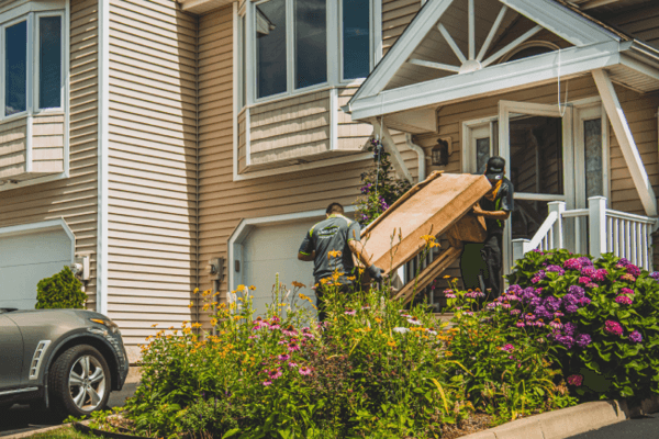 Junk movers carrying couch out of home.