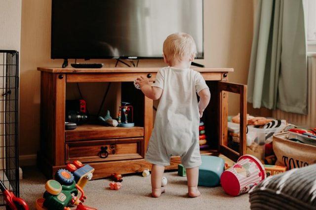 Toddler in a living room with a mess of toys