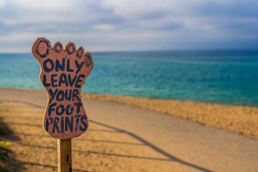 Only Leave Your Footprints sign on a beach