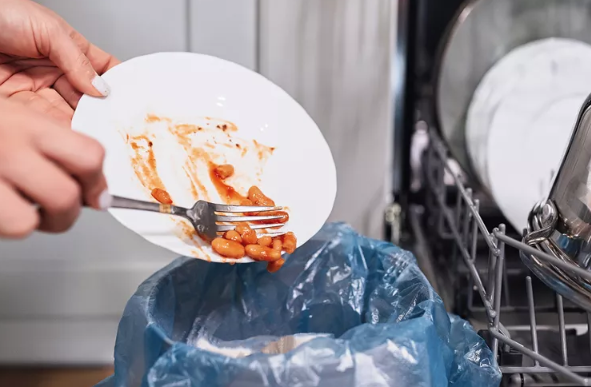 person scrapping beans into the trashcan 
