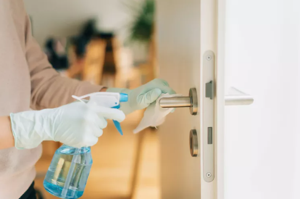 person with green gloves washing door handle